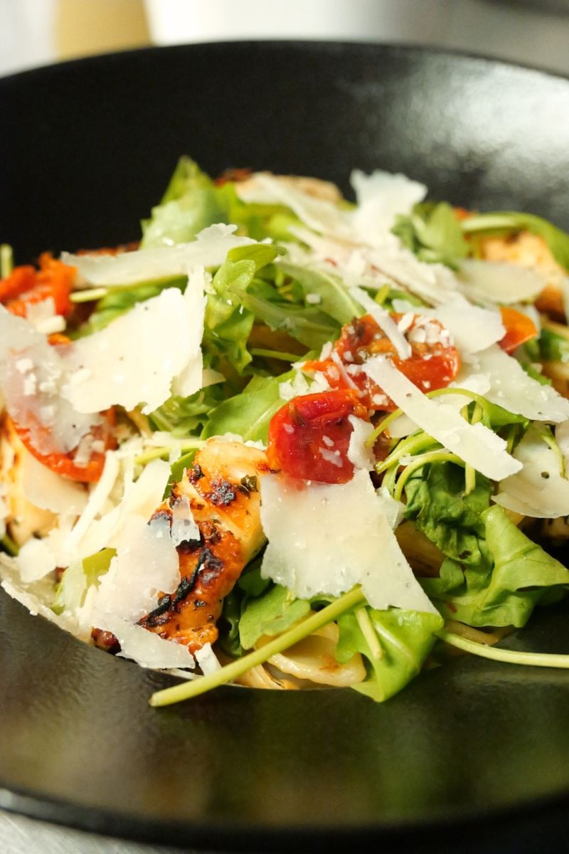 Assiette de pâtes, roquette, tomates confites et copeaux de parmesan