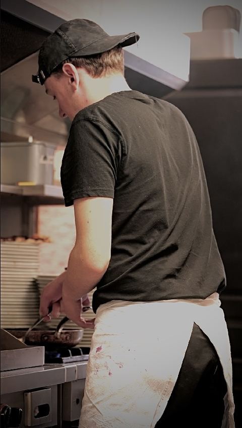 Un cuisinier au fourneau, poêle en main