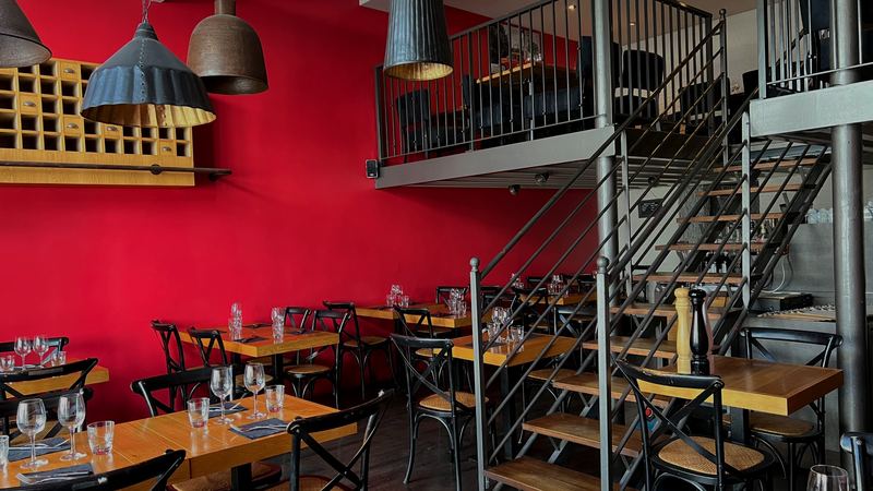 Tables dressées devant le mur rouge et le casier en bois